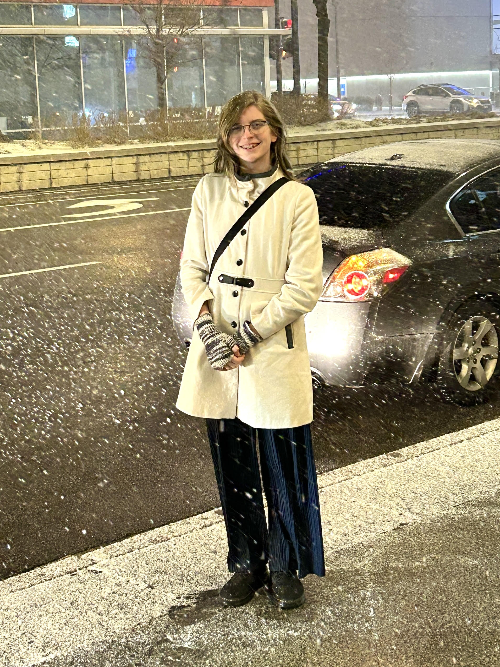 A photo of a blonde creature standing in the snow smiling at the camera